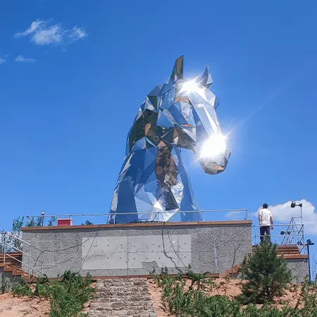 Geometric faceted stainless steel horse head sculpture reflecting sunlight like disco ball