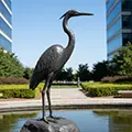 Bronze blue heron statue standing in garden pond