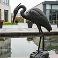 Bronze blue heron statue standing in garden pond