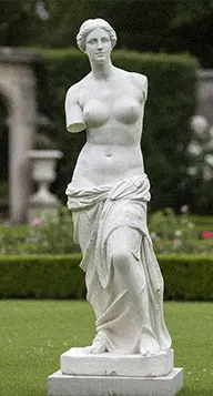 White marble Venus de Milo statue replica standing in a green garden