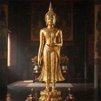 Elegant gold leaf Thai Buddha statue with sharp features and ushnisha, showcasing traditional Thai style.