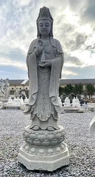 Stone Guanyin statue, highlighting natural granite or marble as a grounded material for Asian garden statues.