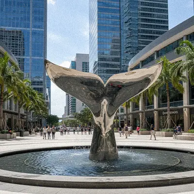 Giant bronze whale tail sculpture diving into water