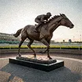Bronze racehorse with jockey statue crossing finish line