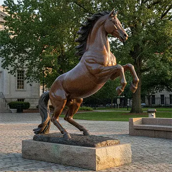 Large bronze rearing horse statue on stone base in city square