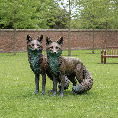 Red fox bronze garden statue standing near grass