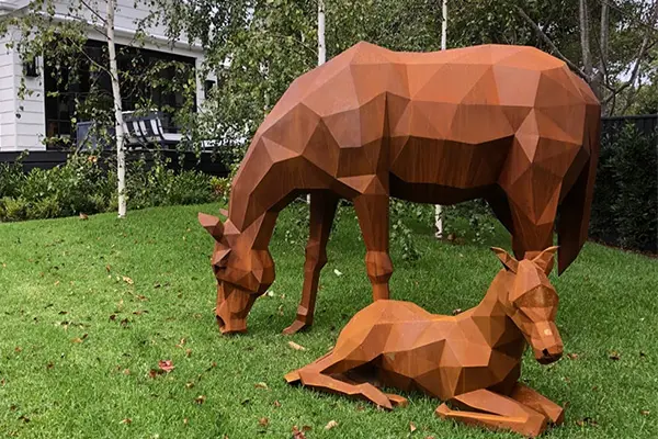 Corten steel geometric horse sculpture group with rusty orange patina in park setting