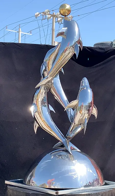 Large stainless steel abstract dolphin sculpture on pool deck