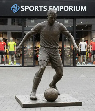 Custom bronze football player statue capturing a tackling action, featuring detailed pads and helmet.