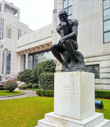 Bronze Thinker statue installed on a white pedestal in a university campus