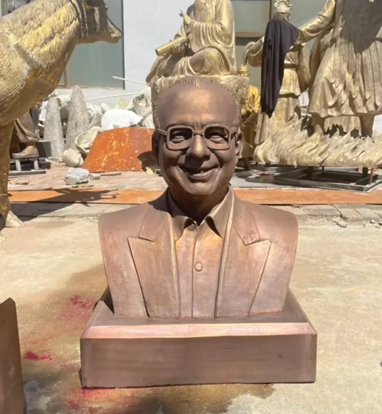 Life-size custom bronze bust of a smiling man with glasses, showing realistic patina finish.