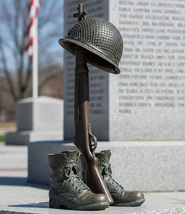 Bronze soldier cross memorial statue in cemetery setting