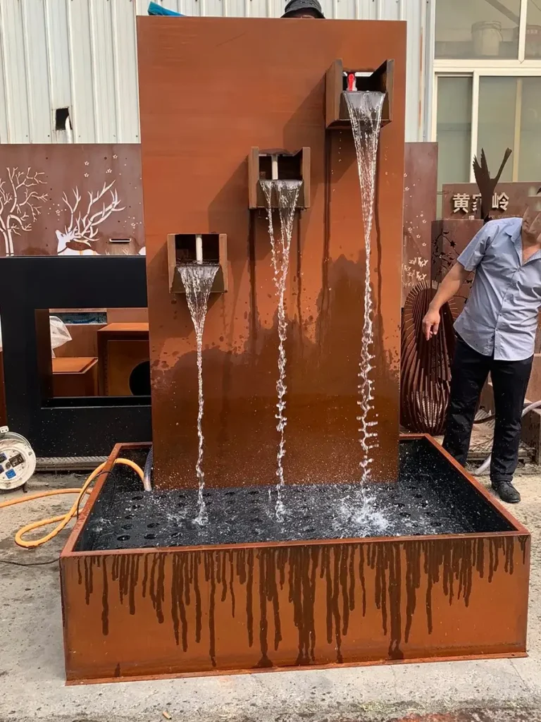 Weathering steel double water curtain fountain undergoing factory testing, with workers observing the water flow.