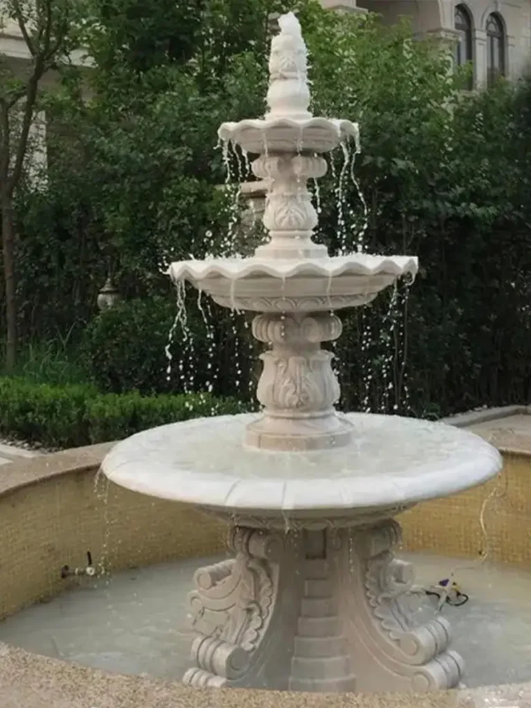 Four-tier white marble estate fountain fully installed and operating with smooth water spillover on all levels.