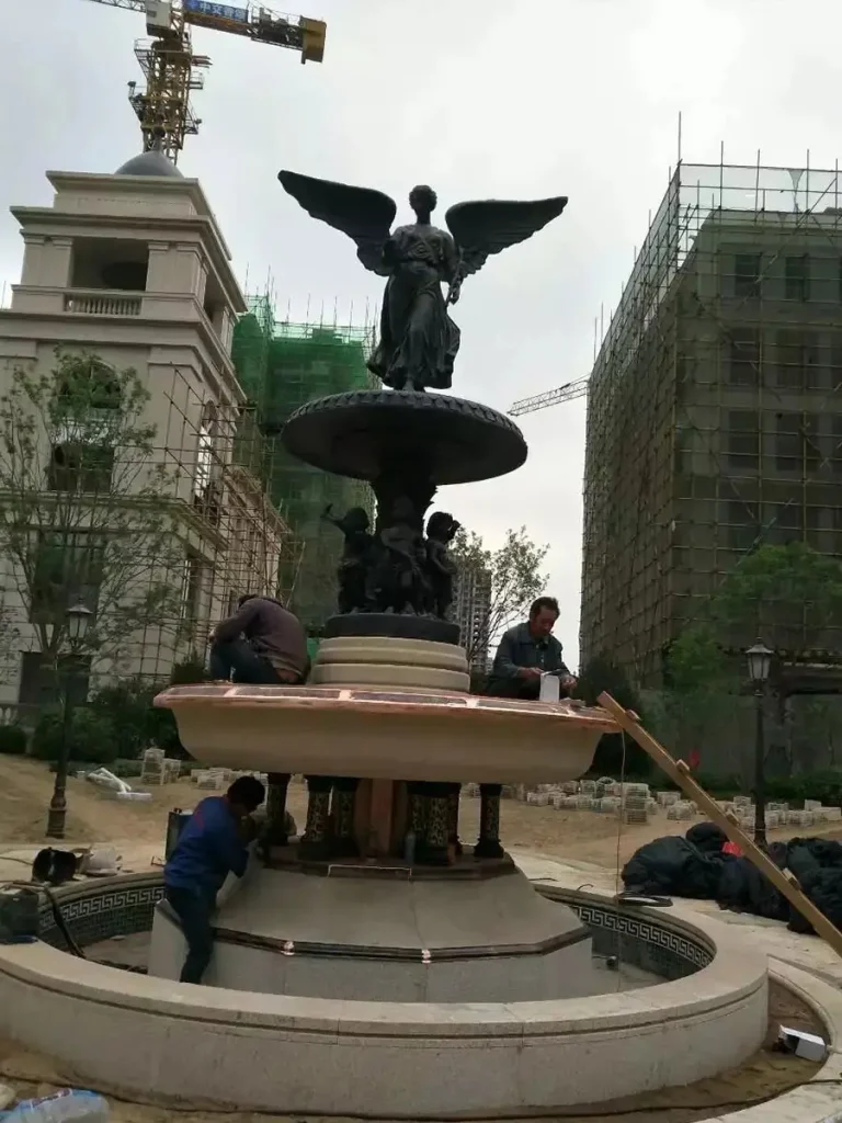 Installation site of a monumental bronze St. Michael the Archangel fountain, showing the detailed religious sculpture being mounted for a public plaza.