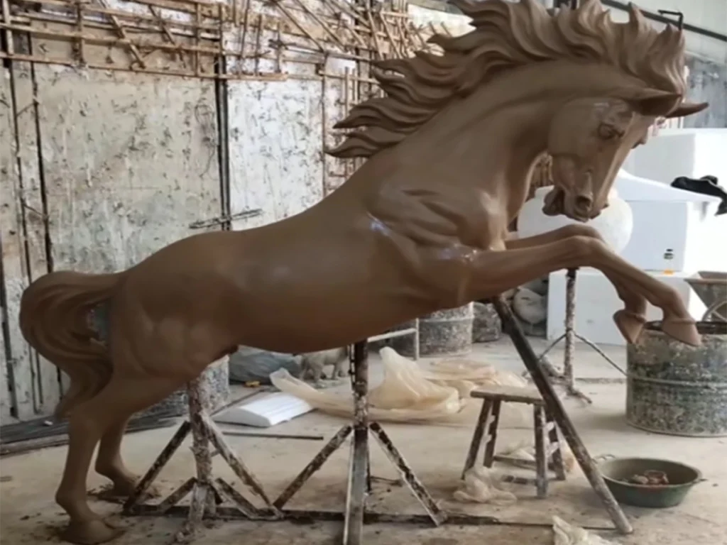 Artists sculpting a life size horse clay model during custom bronze horse statue production process