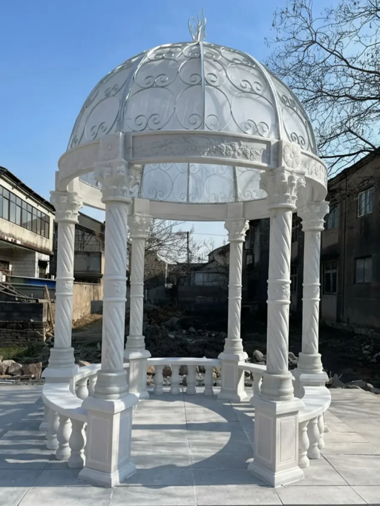 Close-up of hand-carved marble column showing deep relief floral patterns and natural stone crystalline texture in luxury garden installation.