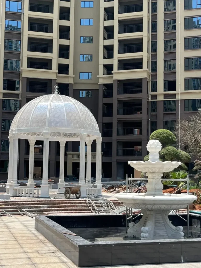 Side angle view of white marble gazebo installed on concrete foundation highlighting structural stability and design symmetry