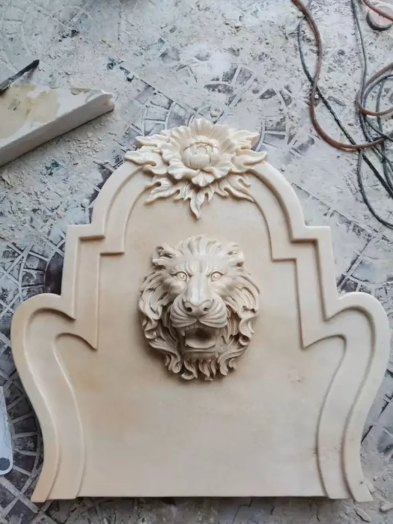 Hand-carved marble lion head wall fountain backplate with decorative arched top before installation.