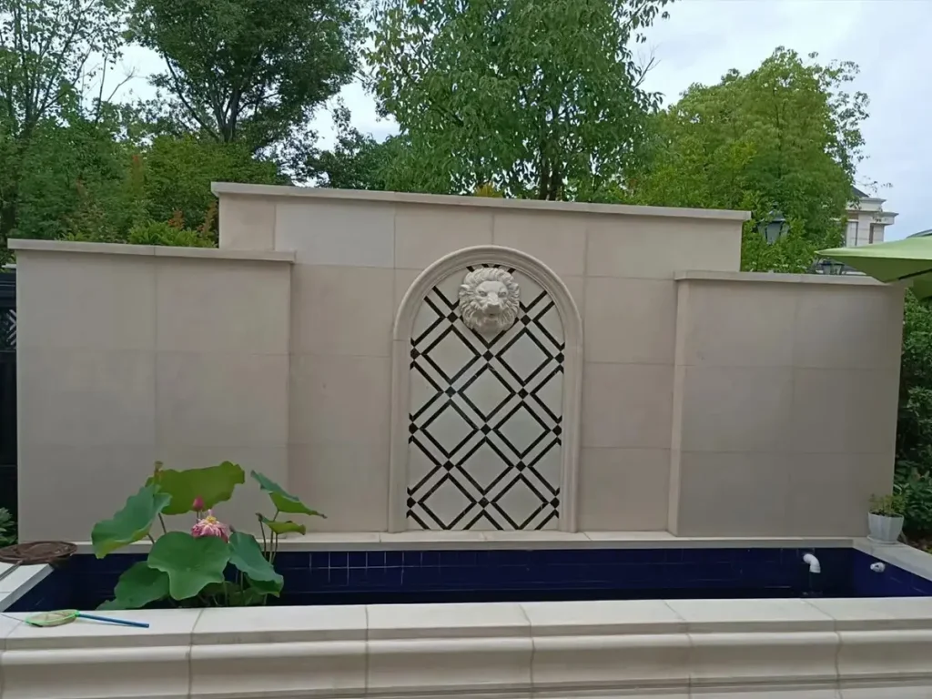 Modern courtyard stone wall fountain feature with geometric panel design and long rectangular basin.
