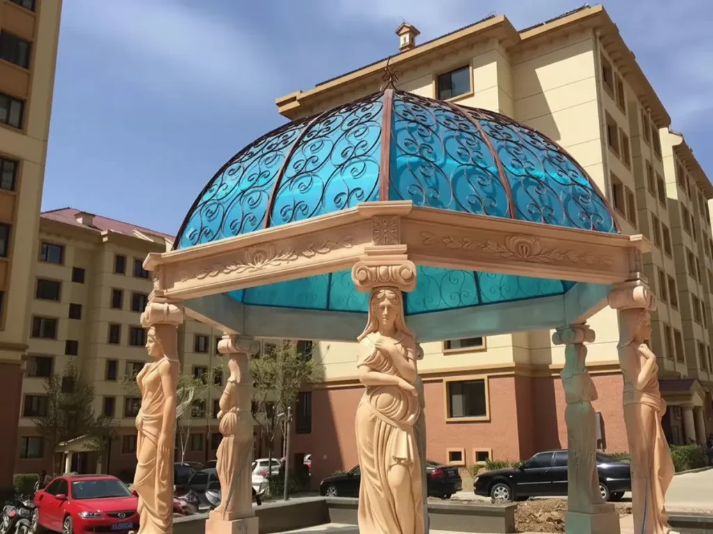 Red marble column gazebo topped with wrought iron birdcage dome, iron roof structure installed over hand-carved stone base.