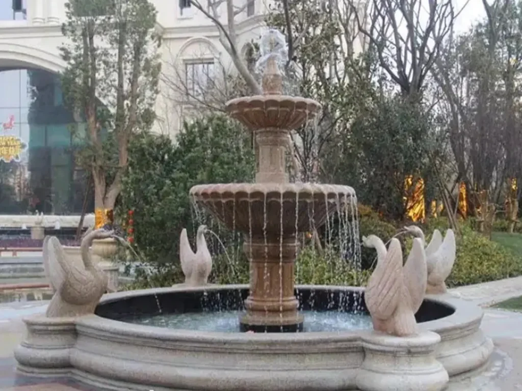 Running water fountain featuring marble swan statues in the pool, creating a lively garden water feature.