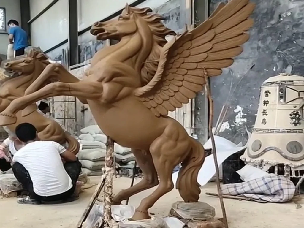 winged horse clay sculpture model being handmade in traditional lost wax casting workshop
