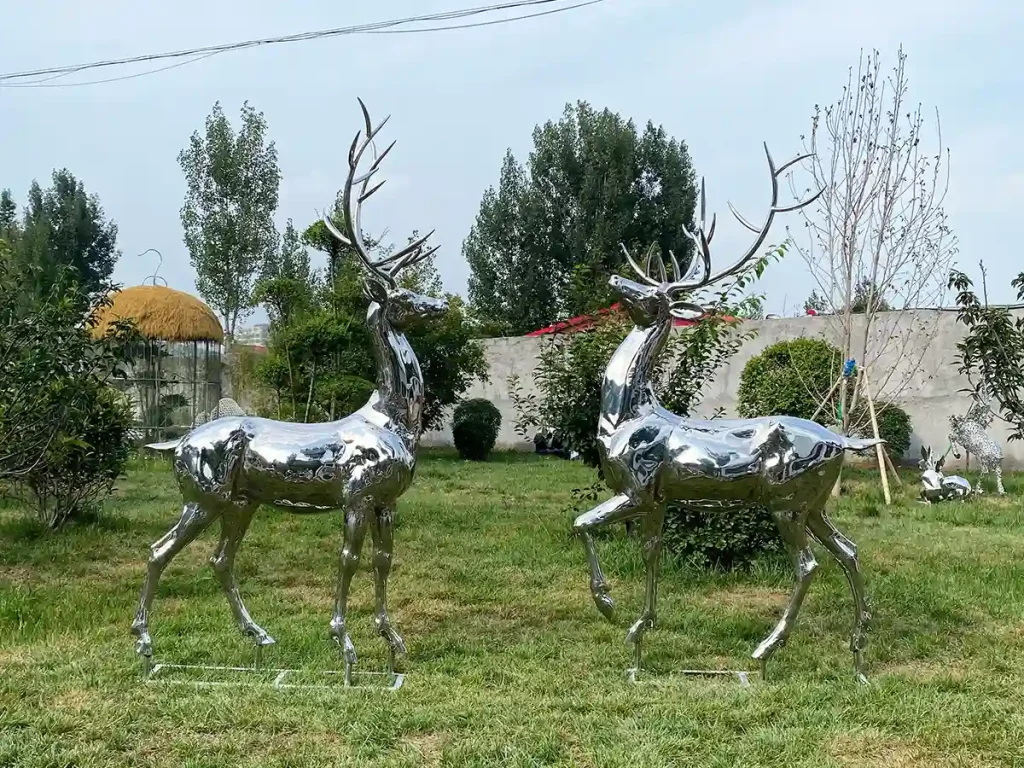 A majestic pair of mirror-polished stags placed gracefully on a serene garden lawn. Acting as the ultimate visual punctuation in landscape architecture, this animal sculpture metal guides the eye and slows movement, demonstrating the quiet power of reflective art.