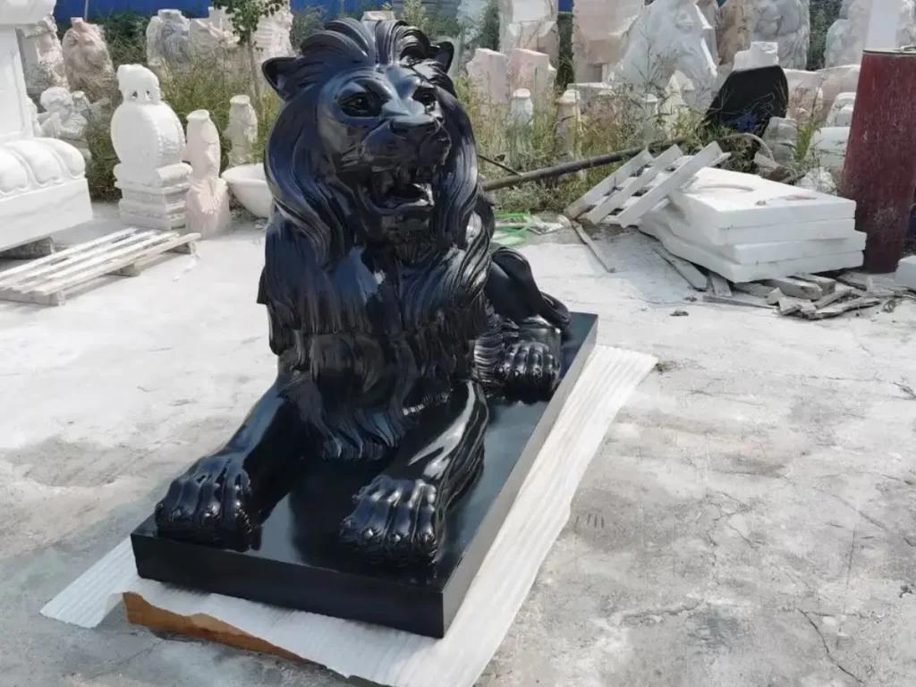A highly detailed black granite resting lion statue with an intricate mane, serving as a quiet but vigilant guardian for an estate driveway.
