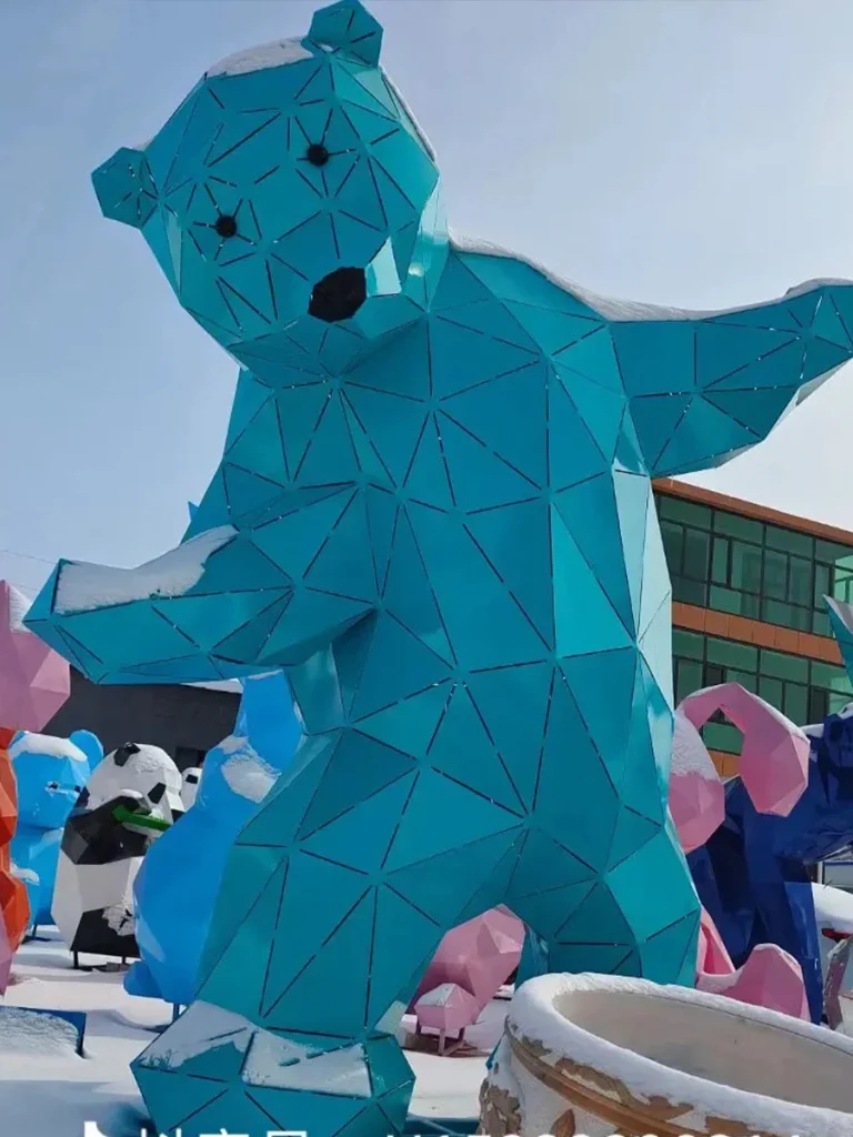 A monumental bright blue painted stainless steel bear sculpture featuring a faceted, geometric design with embedded lighting channels. Striking an upright, welcoming posture, this modern architectural art piece serves as a globally recognized marker for vibrant city centers.