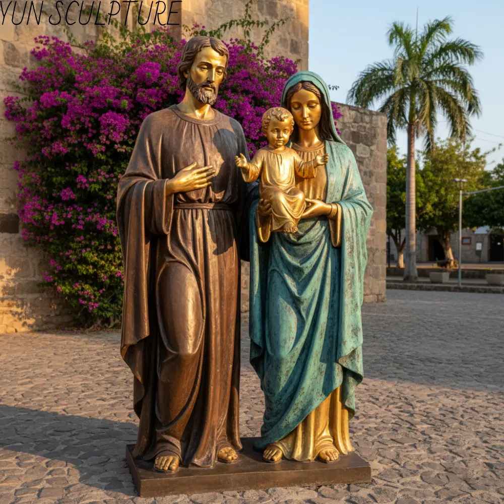 A bronze Holy Family statue in a church plaza, featuring a four-color zone patination system with Joseph in statuary brown and Mary in a verde antique mantle.