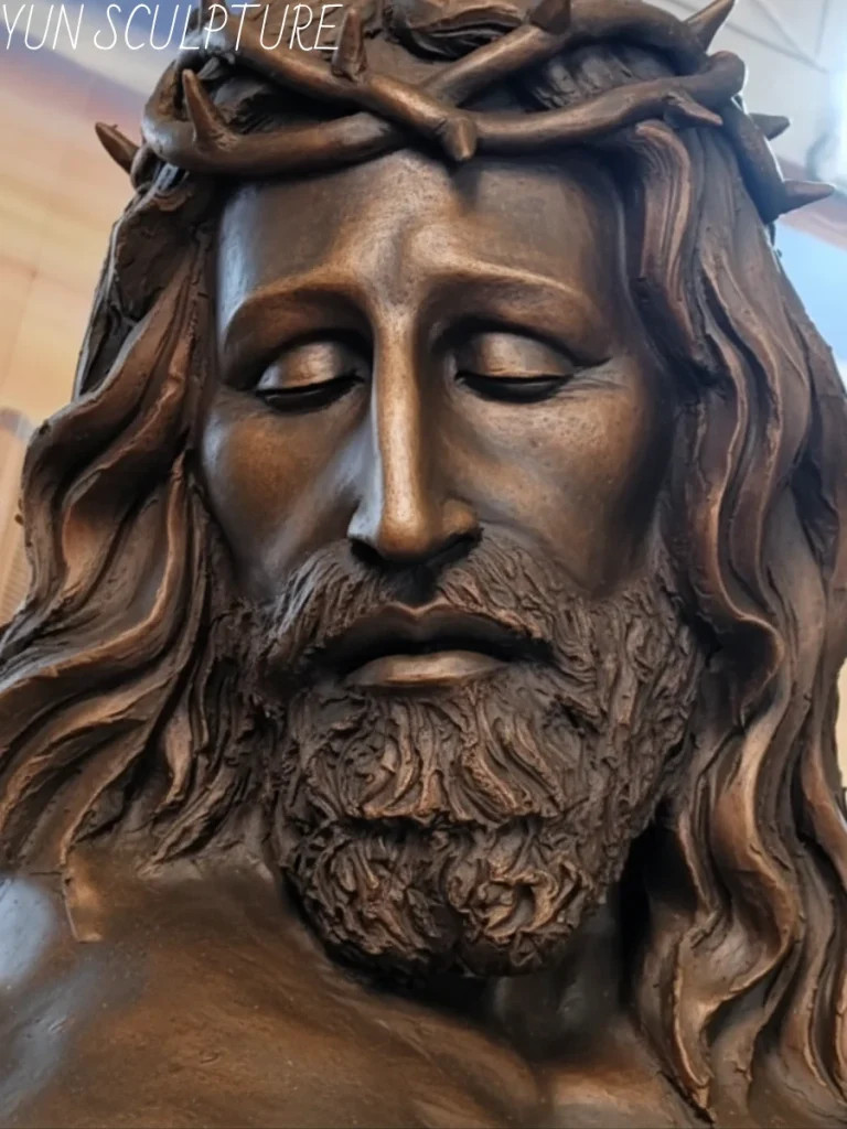 An extreme close-up of a magnificent bronze Jesus statue, focusing on the intricately cast Crown of Thorns and the serenely bowed face. Demonstrating the master-level lost-wax casting process, this stunning metalwork perfectly captures the complex negative space and physically plausible interweaving of each individual thorn pressing into the hair strands, effortlessly solving dozens of technical casting problems in one sacred composition.