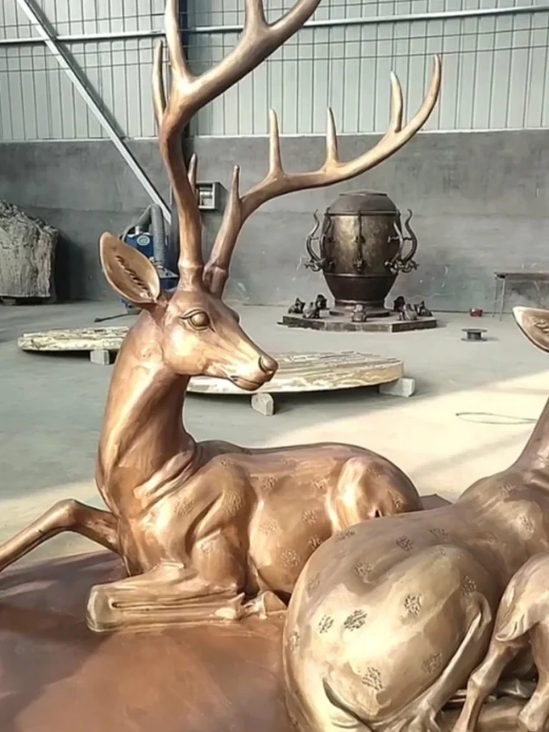 A striking close-up of a finished bronze stag statue, highlighting its proud neck angle and gracefully branching antlers. The freshly applied hot chemical patina gives the durable metal a luminous, warm golden-brown finish that will gracefully evolve over time in the elements.