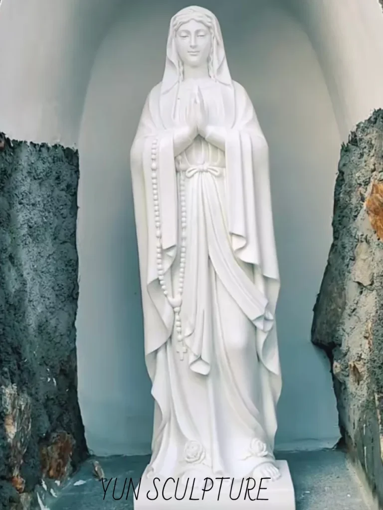 An angled, tight shot of the white marble Virgin statue standing inside the grotto's recessed cavity. The dark, unfinished interior walls explicitly showcase the calculated 20% negative space around the base, a crucial structural requirement that allows for safe heavy-machinery installation rigging without damaging the delicate sculpture.