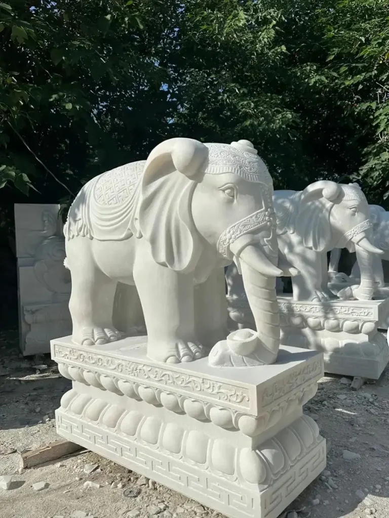 A premium, life-size white marble elephant sculpture bathed in sunlight at a manufacturing factory. Its imposing size and tranquil posture perfectly reflect the powerful presence and cultural reverence associated with monumental elephant statues throughout history.
