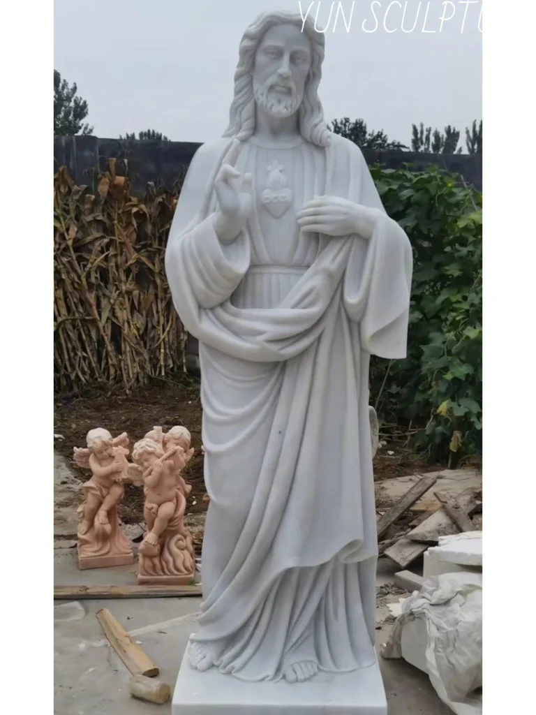 A magnificent, hand-carved white marble Divine Mercy Jesus statue standing in a bustling sculpture workshop, awaiting final delivery. Perfectly suited for Catholic Parish and Diocese commissions, this majestic stone figure demonstrates our strict adherence to traditional iconographic standards, ensuring smooth approval from parish building committees and diocesan art offices for major sanctuary renovations and new chapel constructions.