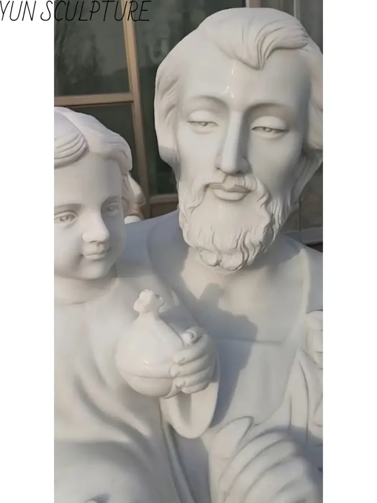 Close-up detail of a marble carving showing Saint Joseph's protective gaze toward the infant Jesus.