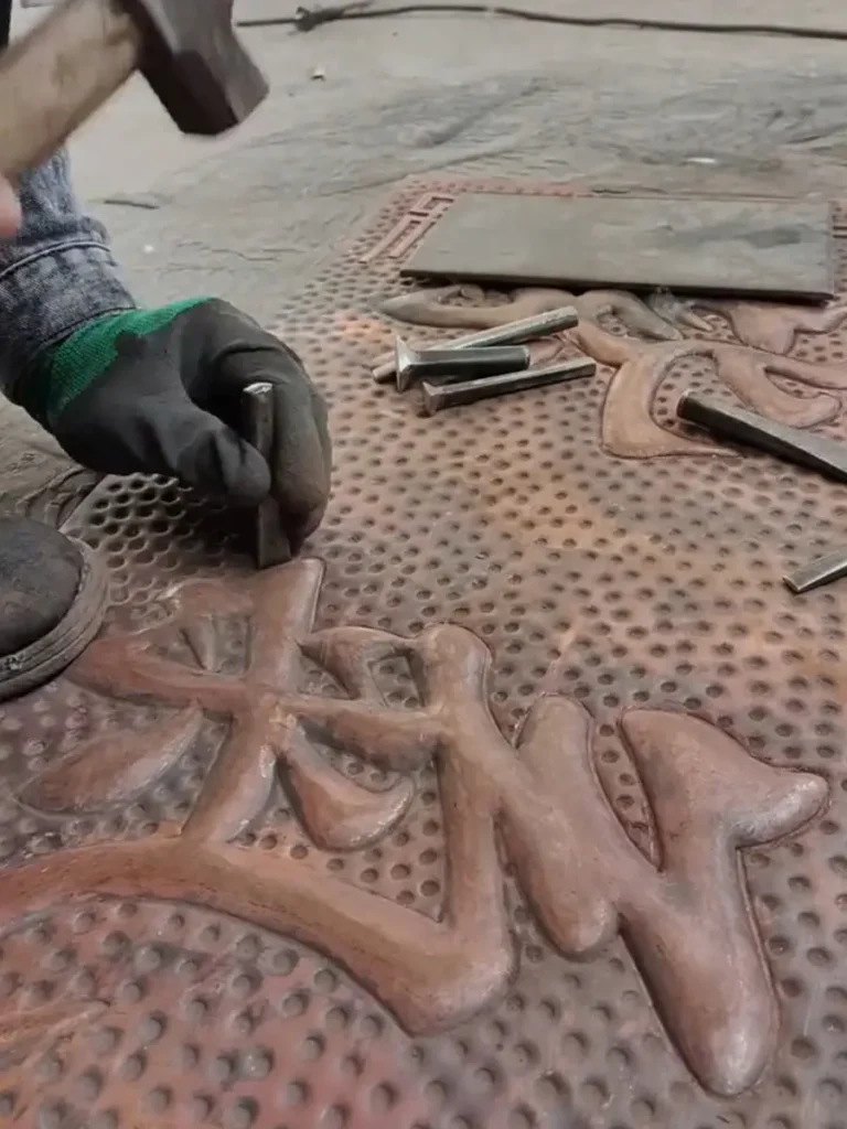 Using a specialized chisel to outline and refine the intricate textures of the direct metal sculpture.