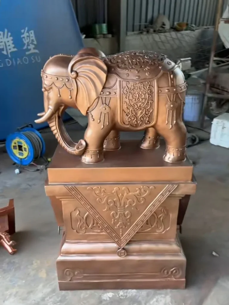 A custom cast bronze elephant sculpture with its trunk directed downwards, displayed in a workshop. Homeowners seeking emotional balance and family growth often prefer this trunk-down style to symbolize the gathering of wealth and introspective energy.