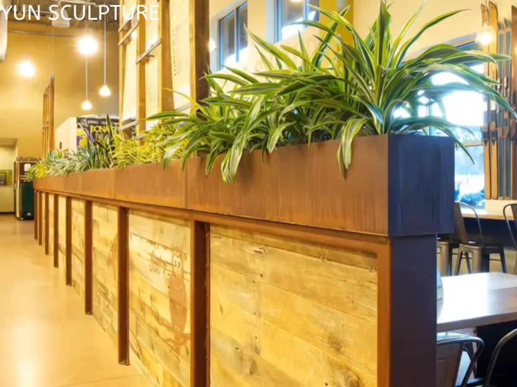 A linear custom Corten steel planter used as an indoor architectural divider, demonstrating the precision and aesthetic versatility of weathering steel in public interiors.