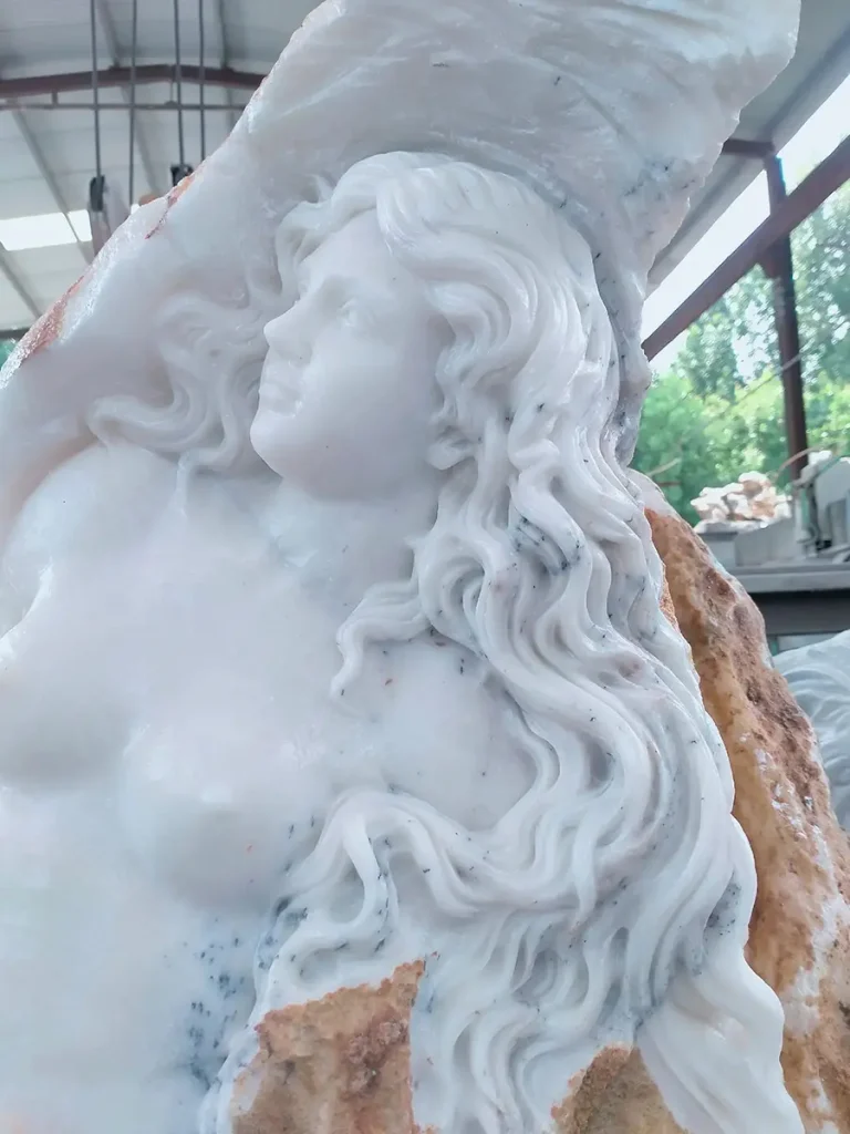Close-up of a marble mermaid sculpture's face and flowing hair, highlighting the precision of hand-carving techniques in natural stone.