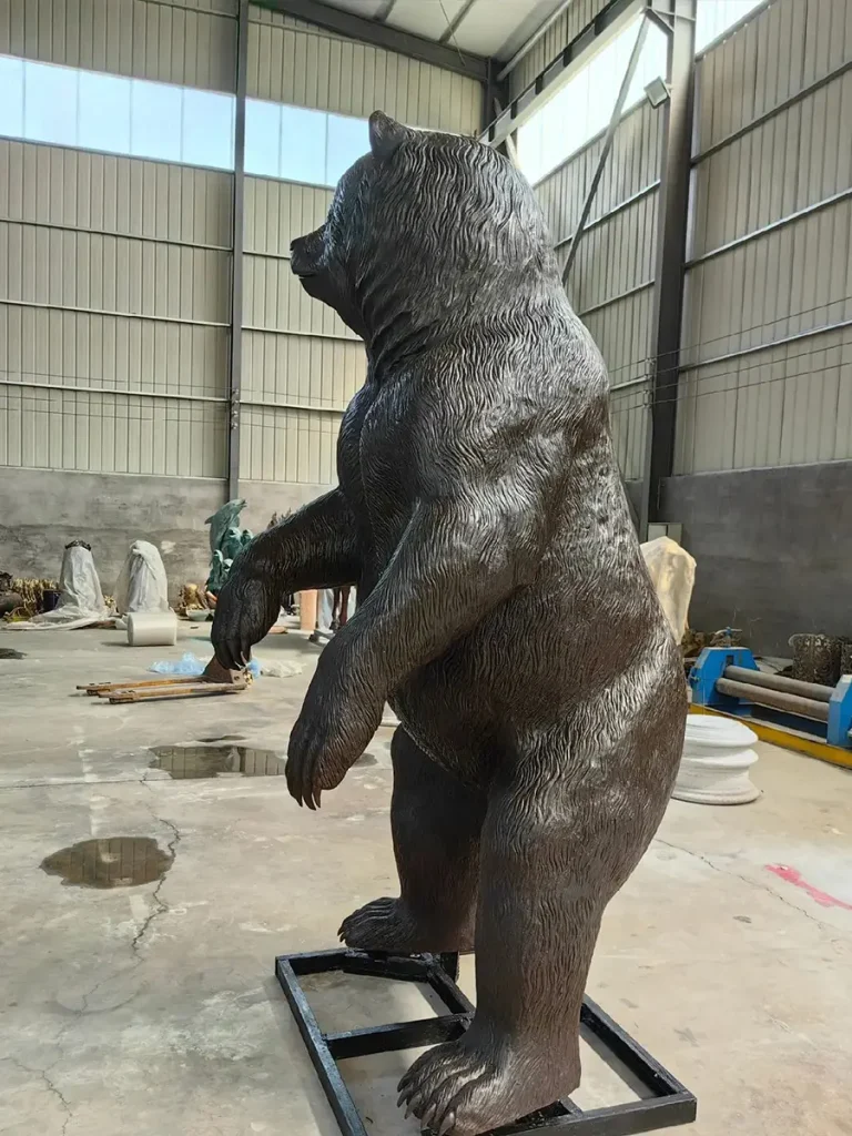 Side profile of a completed life-size bronze bear statue standing proudly on a metal mounting frame. The rich, dark finish exemplifies the weight, depth, and timelessness of classical bronze sculpture, which will continue to develop a beautiful natural protective patina over time.