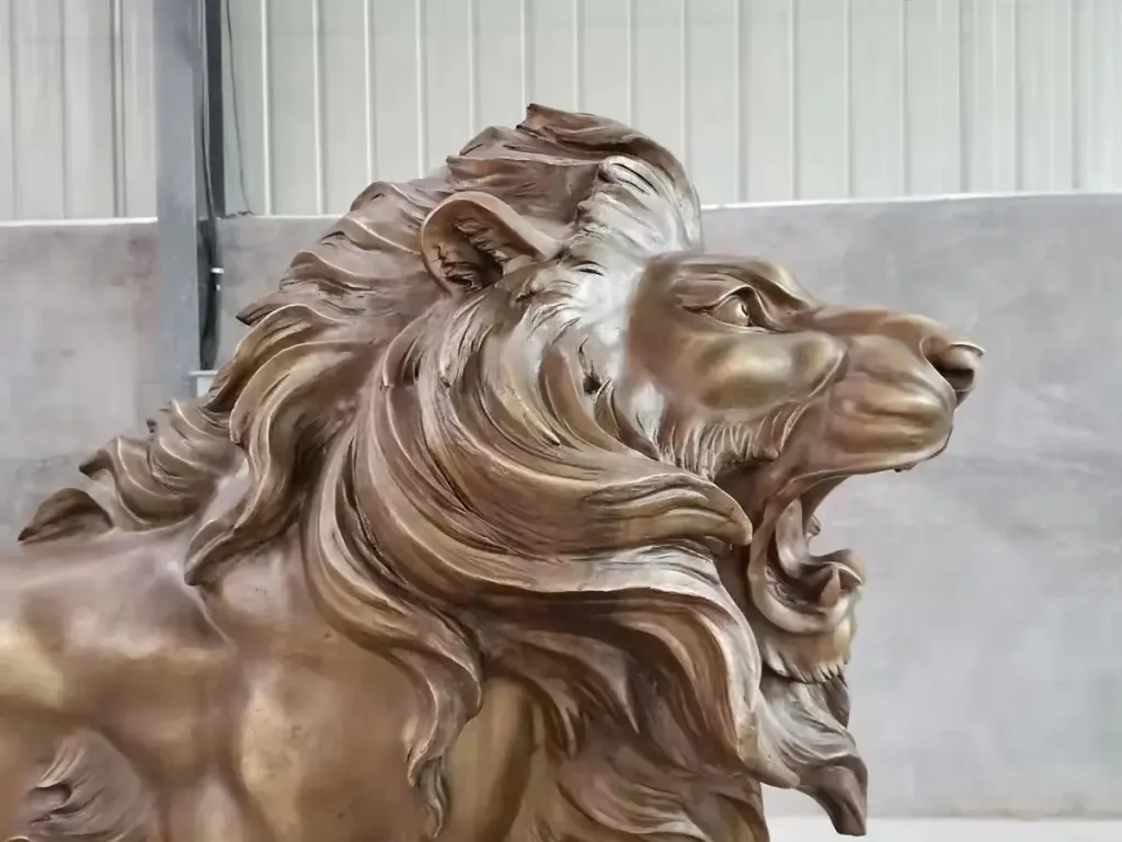 Close-up profile of a completed bronze lion statue's head and mane. The gleaming metal perfectly preserves the layered mane, facial tension, and subtle anatomical details from the original clay mold, showcasing the exceptional precision of traditional bronze casting.