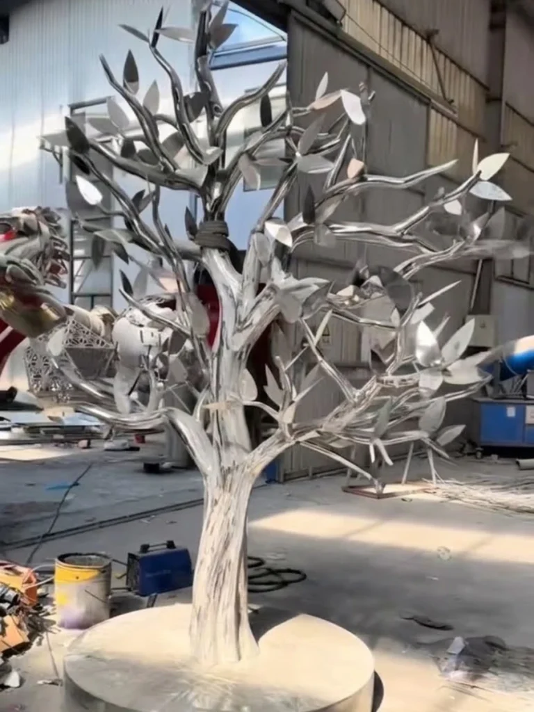 Stainless steel tree sculpture with polished metal leaves in factory