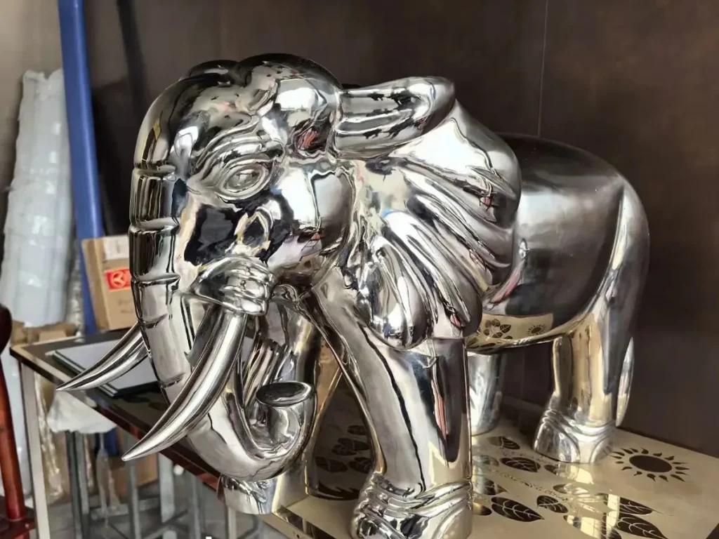  Front view of a highly detailed, realistic stainless steel elephant statue with its trunk pointing down. Crafted from premium 316 stainless steel using meticulous forging techniques, it serves as a modern Feng Shui elephant symbolizing gathered wealth and structural stability for modern architecture.