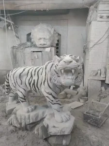 Carved tiger statue in workshop setting.