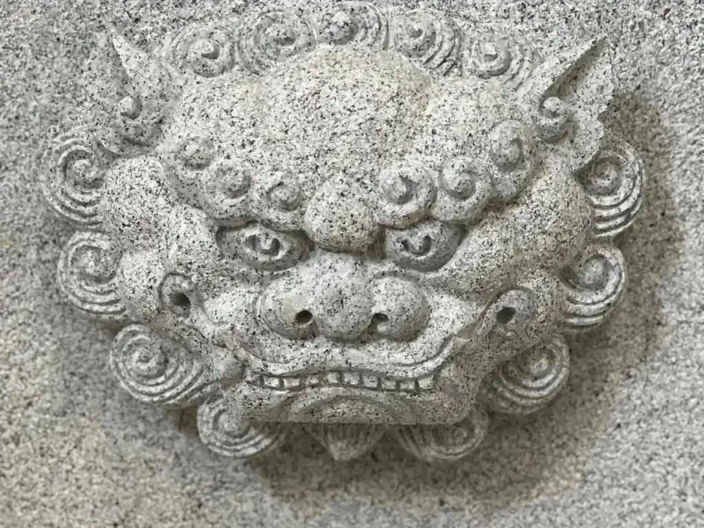 A close-up shot of an intricate lion head relief carved into natural granite, showcasing the craftsmanship behind high-end architectural stone planters.