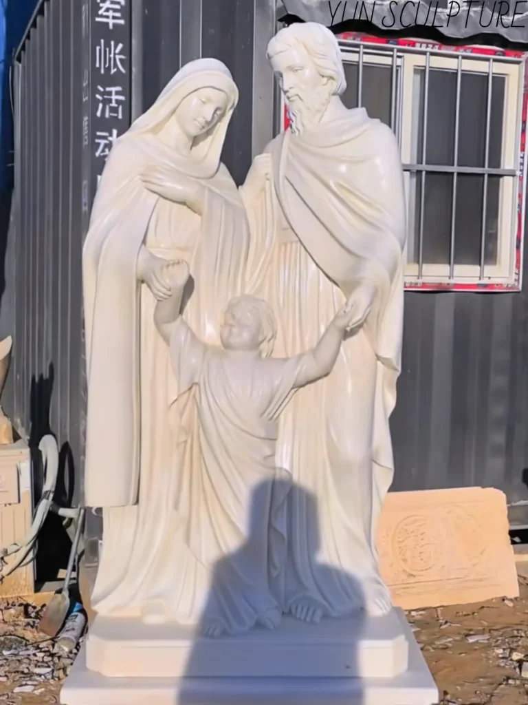 A full-length white marble Holy Family statue featuring Joseph, Mary, and the child Jesus, demonstrating the luminous and translucent quality of high-quality interior stone carving.
