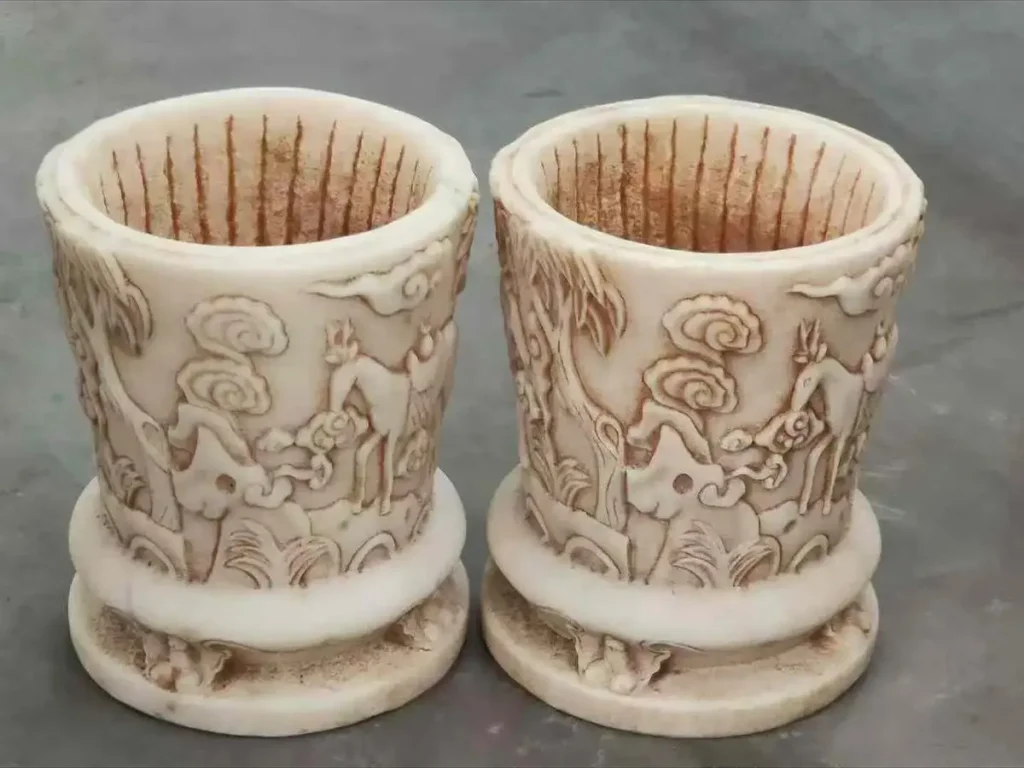 A pair of intricate hand-carved stone planters featuring traditional narrative reliefs, showcasing the surface details that require gentle pH-neutral cleaning.