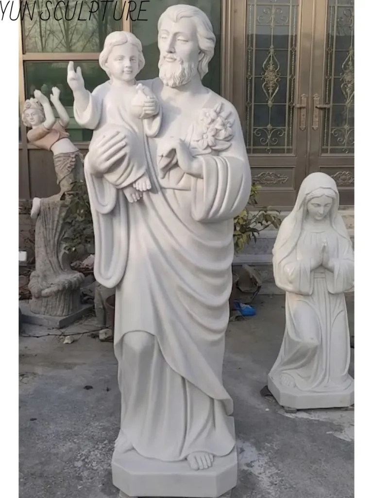 Full-length marble statue of Saint Joseph holding Jesus, positioned to complement a Mary and Joseph statue group.